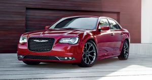 Beautiful picture of a red 2018 Chrysler 300 parked in front of a garage.
