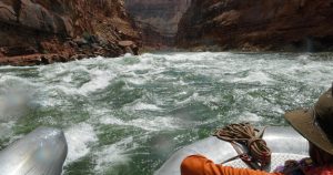 A raft going down light rapids through a canyon.
