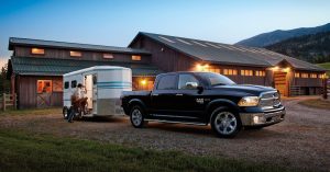 A black 2019 Ram 1500 Classic attached to a horse trailer outside a mountain ranch.